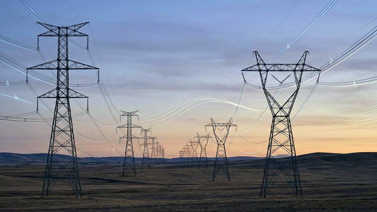 High-voltage electrical transmission towers and power lines stretching across an open landscape against a twilight sky